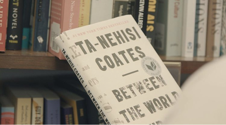 A copy of Ta-Nehisi Coates' Between the World and Me against a backdrop of books on shelves